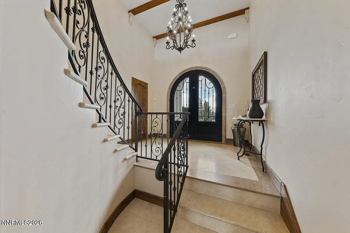 Two-story foyer with a curved iron staircase and chandelier