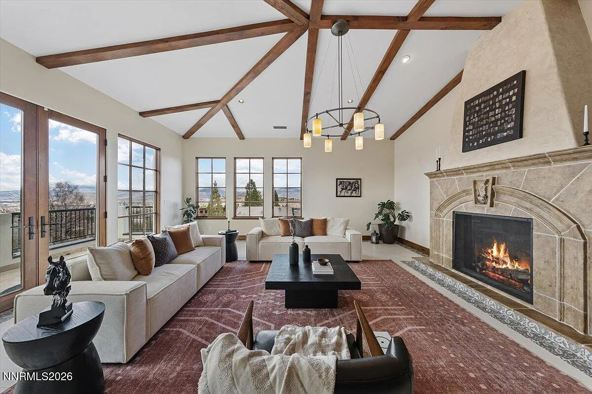 Great room with beamed ceiling, stone fireplace and tall windows