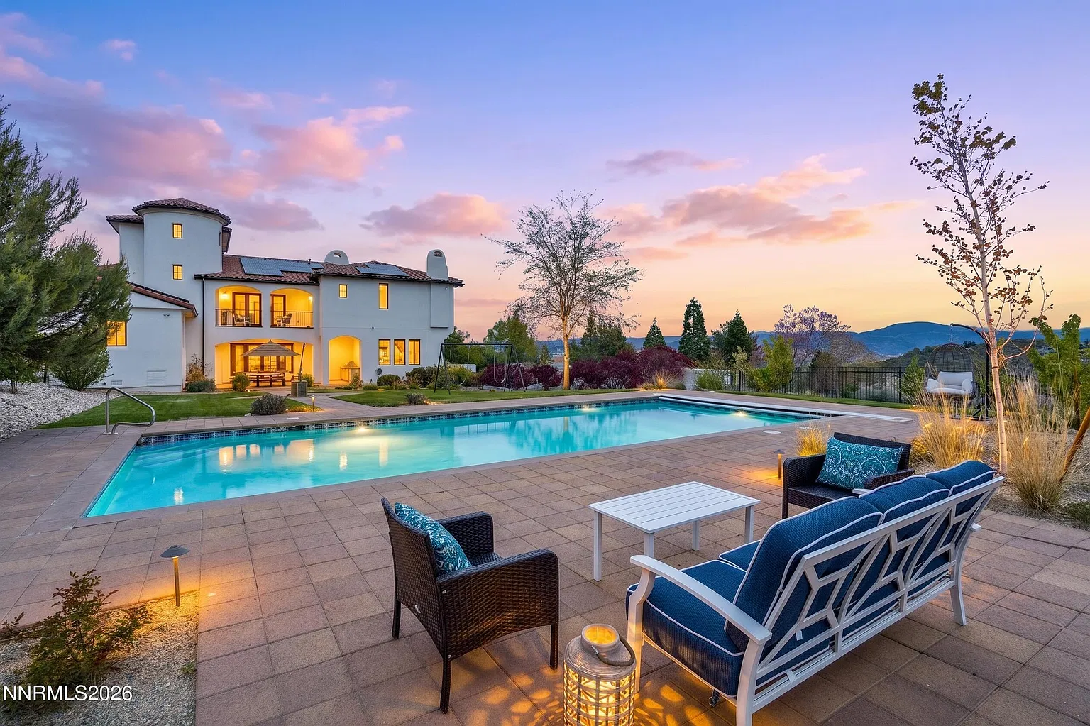 The house at dusk from across the pool, windows lit