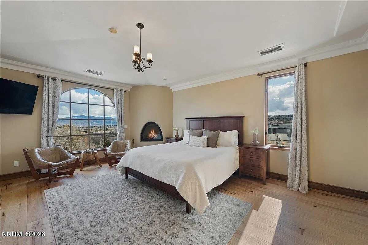 Primary bedroom with a kiva fireplace and arched window